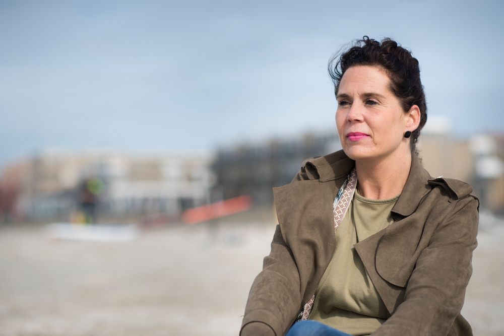 Vrouw zit op het strand kijkt in de verte