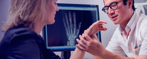 Arts onderzoekt de hand van een vrouw