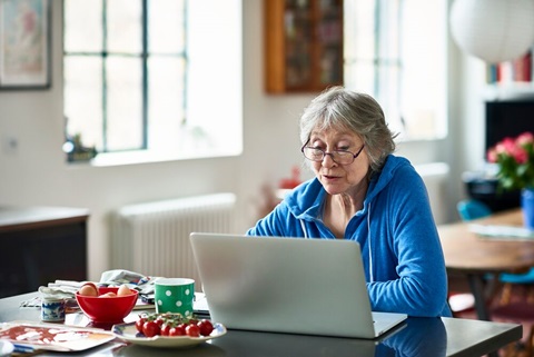 Oudere vrouw zit achter laptop