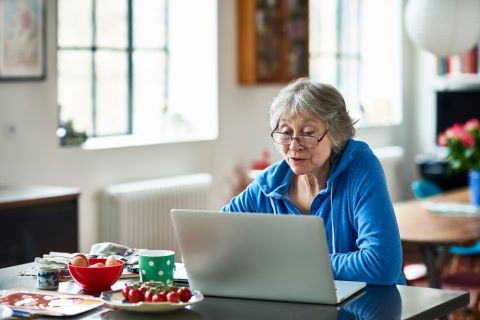 Oudere vrouw zit achter laptop