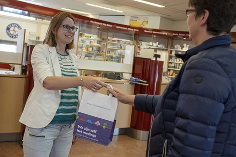 apotheker geeft zakje mee aan klant