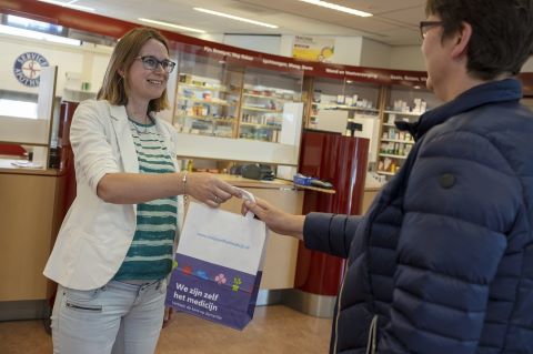 apotheker geeft zakje mee aan klant