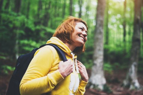 vrouw met geel vest wandelend in het bos