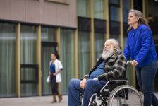 Vrouw duwt oude man in rolstoel