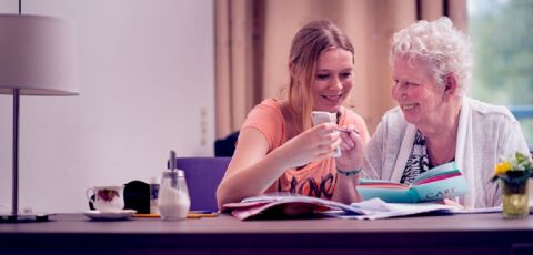 Kleindochter helpt oude vrouw met mobiele telefoon
