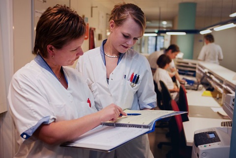 Verpleegkundigen in overleg achter de ziekenhuisbalie