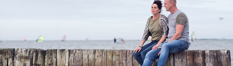man en vrouw zittend aan de rand van het strand