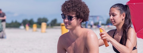 Meisje smeert jongen in met zonnebrand