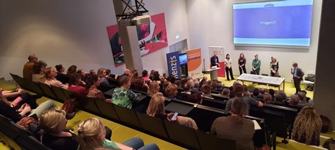 Mensen in zaal kijken naar presentatie
