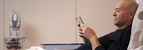 man leest op tablet in ziekenhuisbed